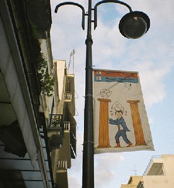 Political cartoon, public banner, Patras, Greece.